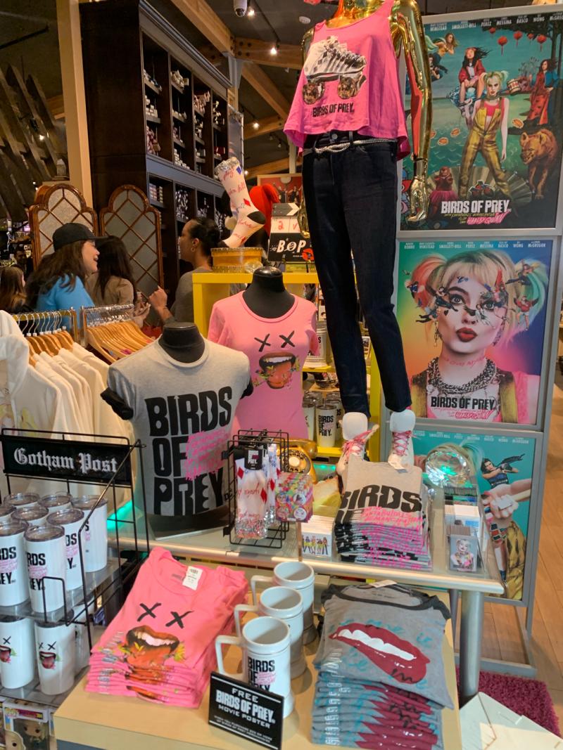 Store display with 'Birds of Prey' custom merchandise, including t-shirts and posters.